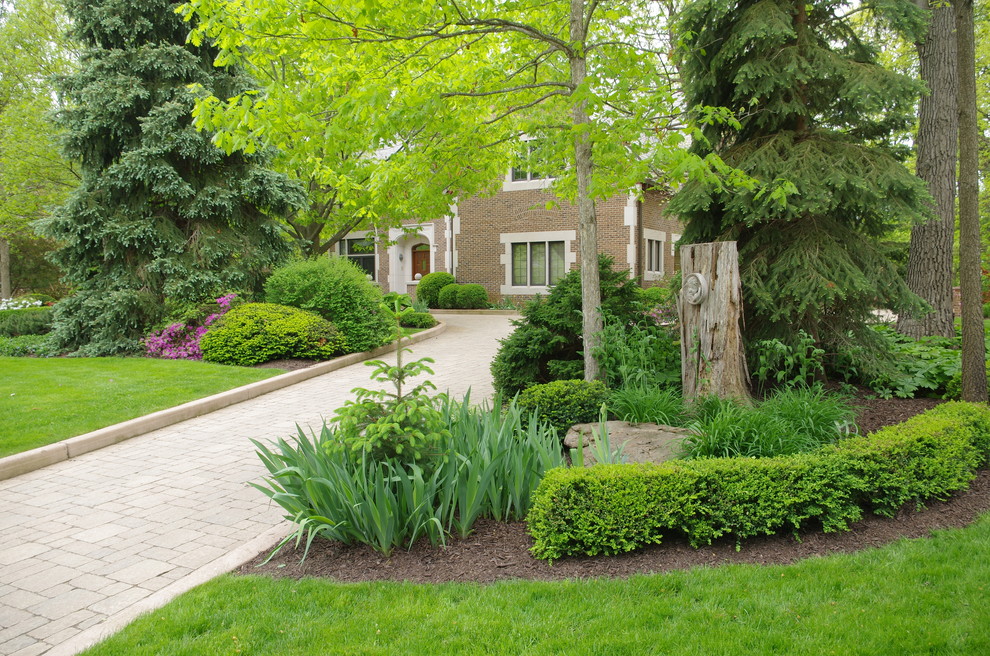 Inspiration for a mid-sized country front yard shaded driveway for summer in Chicago with brick pavers.