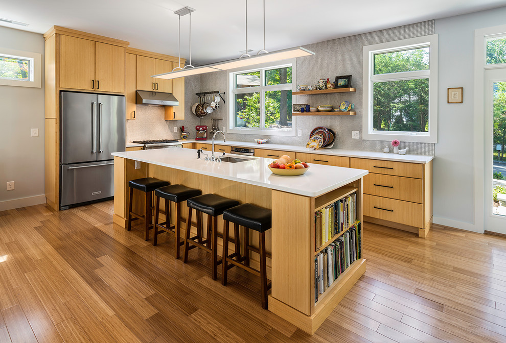 Photo of a contemporary l-shaped kitchen in Bridgeport with an undermount sink, flat-panel cabinets, ceramic splashback, stainless steel appliances, bamboo floors, with island, brown floor, light wood cabinets and grey splashback.