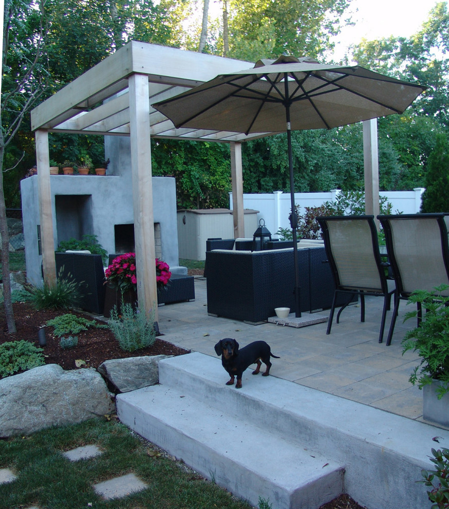 This is an example of a small contemporary backyard patio in Providence with with fireplace, concrete pavers and a pergola.