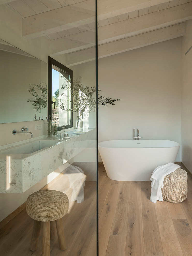 Contemporary bathroom in Barcelona with a freestanding tub, a shower/bathtub combo, a one-piece toilet, white tile, ceramic tile, white walls, medium hardwood floors and an open shower.