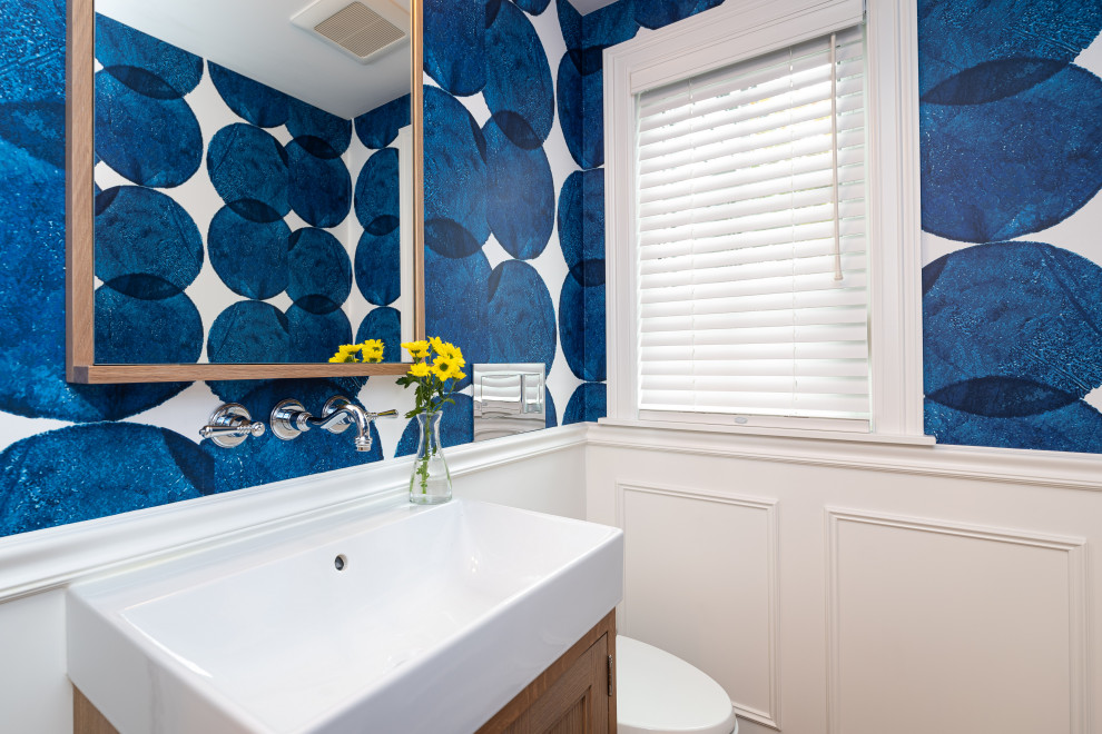 Moderne Gästetoilette mit Kassettenfronten, Schränken im Used-Look, Wandtoilette, weißen Fliesen, blauer Wandfarbe, braunem Holzboden, integriertem Waschbecken, braunem Boden, weißer Waschtischplatte, freistehendem Waschtisch und Tapetenwänden in Seattle