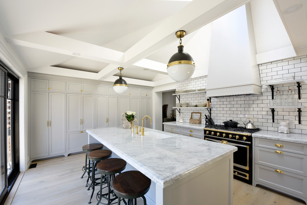 Photo of a transitional galley eat-in kitchen in Ottawa with recessed-panel cabinets, grey cabinets, marble benchtops, white splashback, subway tile splashback, black appliances, medium hardwood floors, with island and an undermount sink.