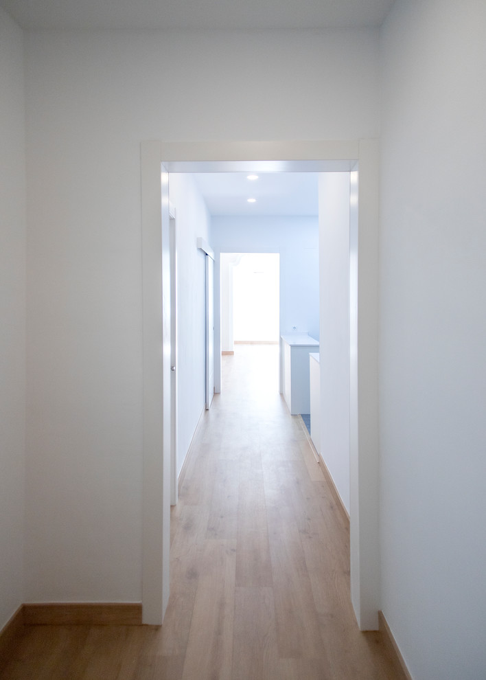 Mid-sized transitional hallway in Barcelona with white walls, light hardwood floors and brown floor.