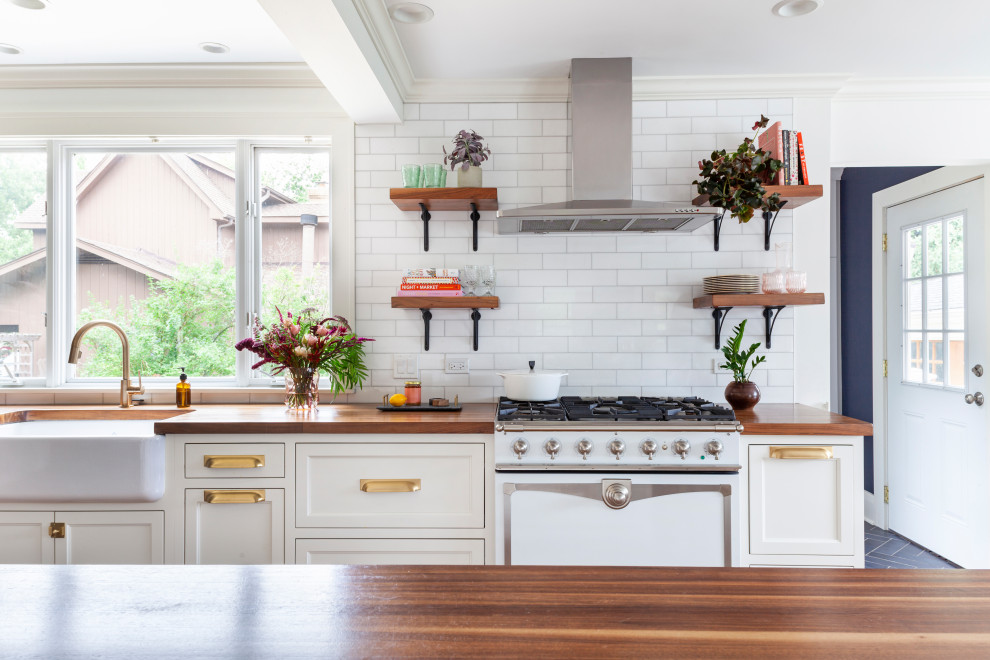 Inspiration for a large eclectic galley eat-in kitchen in Chicago with a farmhouse sink, recessed-panel cabinets, white cabinets, wood benchtops, white splashback, subway tile splashback, stainless steel appliances, medium hardwood floors, with island, brown floor and brown benchtop.