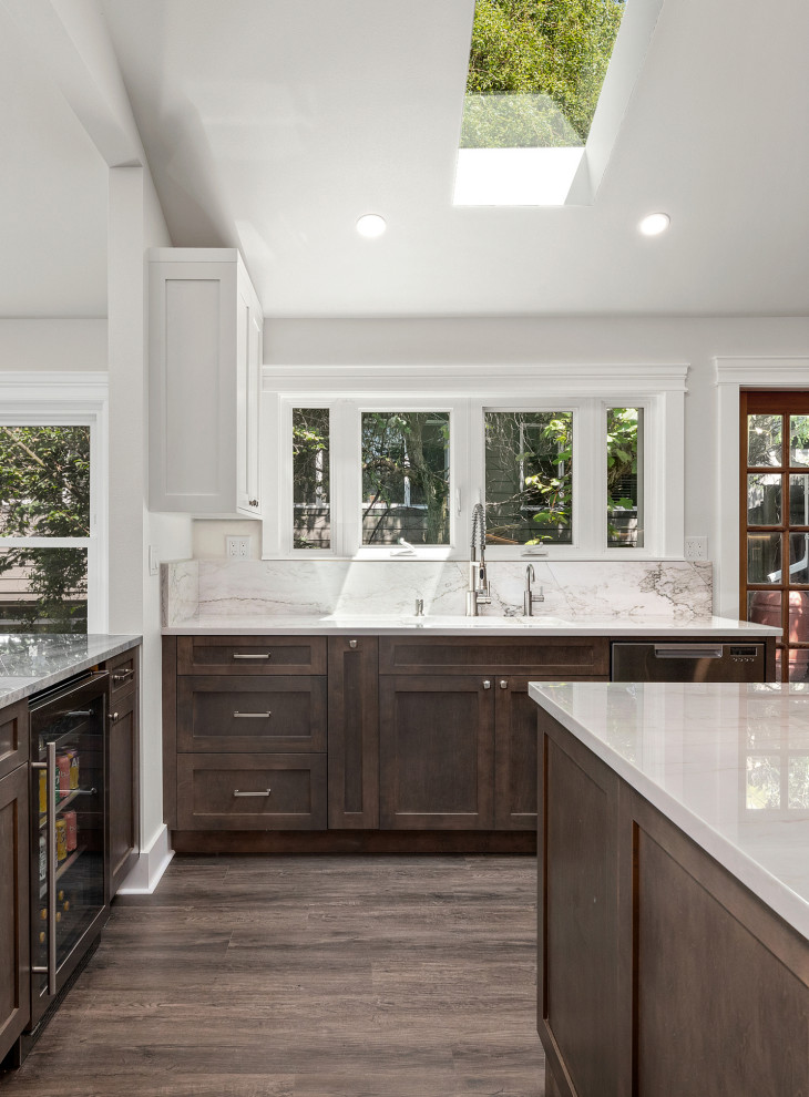 Large transitional u-shaped laminate floor, brown floor and vaulted ceiling open concept kitchen photo in Seattle with an undermount sink, shaker cabinets, dark wood cabinets, quartzite countertops, white backsplash, stone slab backsplash, stainless steel appliances, two islands and white countertops