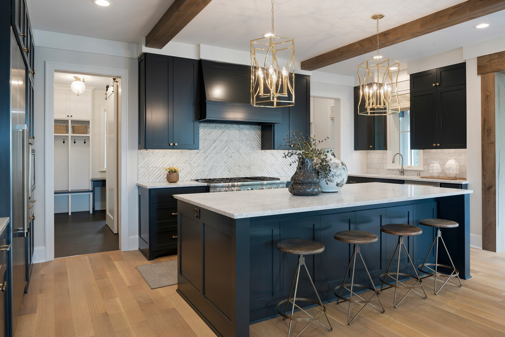 This is an example of a mid-sized transitional u-shaped eat-in kitchen in Minneapolis with shaker cabinets, marble benchtops, white splashback, marble splashback, stainless steel appliances, medium hardwood floors, with island, brown floor and white benchtop.