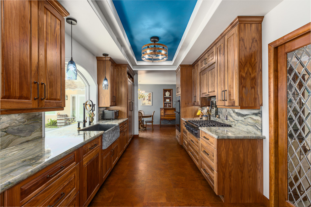 Large traditional galley eat-in kitchen in Santa Barbara with a farmhouse sink, raised-panel cabinets, medium wood cabinets, quartzite benchtops, multi-coloured splashback, panelled appliances, cork floors, no island, brown floor, multi-coloured benchtop, recessed and stone slab splashback.