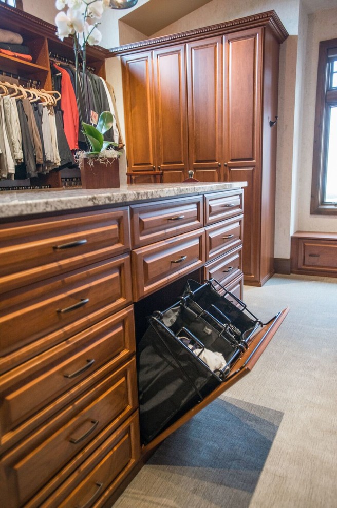 Design ideas for a mid-sized traditional gender-neutral walk-in wardrobe in Denver with raised-panel cabinets, medium wood cabinets, carpet and beige floor.