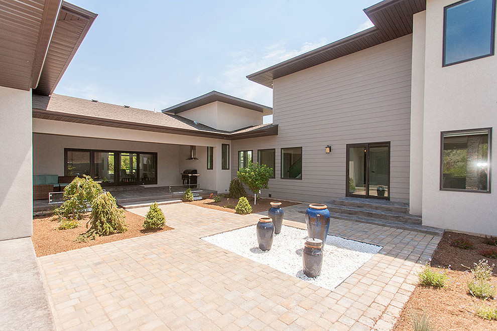 This is an example of a modern courtyard patio in Boise with a fire feature, concrete pavers and a roof extension.