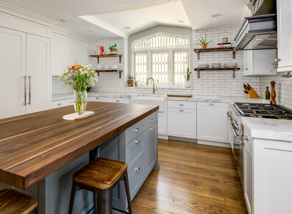 Inspiration for a mid-sized eclectic u-shaped separate kitchen in Denver with a farmhouse sink, flat-panel cabinets, white cabinets, quartzite benchtops, white splashback, brick splashback, panelled appliances, medium hardwood floors, with island, brown floor and white benchtop.