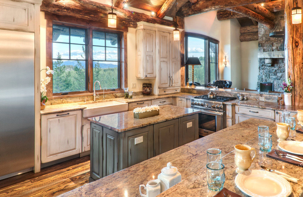Eat-in kitchen - large rustic u-shaped medium tone wood floor and brown floor eat-in kitchen idea with distressed cabinets, granite countertops, stainless steel appliances, an island and beige countertops