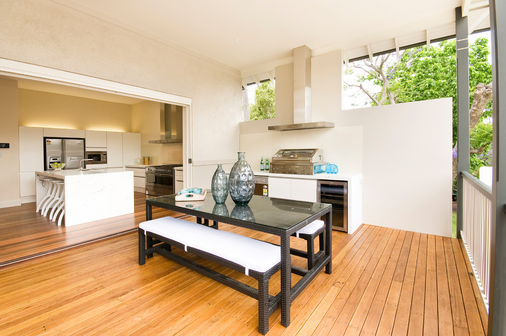 This is an example of a transitional backyard deck in Sydney with an outdoor kitchen and a roof extension.
