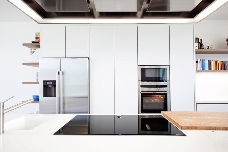 Inspiration for an expansive contemporary l-shaped open plan kitchen in Milan with a drop-in sink, flat-panel cabinets, white cabinets, solid surface benchtops, white splashback, stainless steel appliances, marble floors and with island.