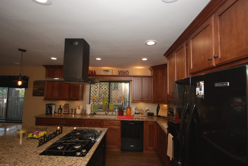 Inspiration for a timeless u-shaped eat-in kitchen remodel with an undermount sink, shaker cabinets, brown cabinets, quartz countertops, beige backsplash, glass sheet backsplash and black appliances