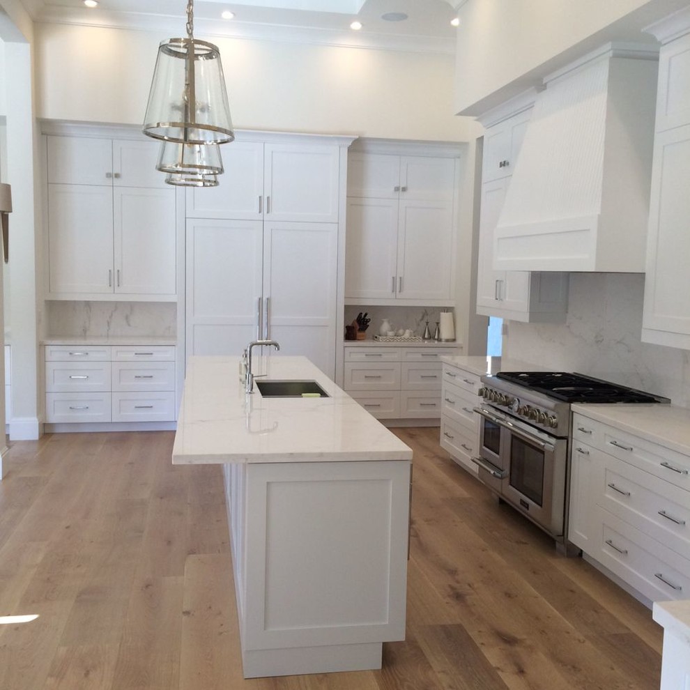 Example of a large transitional u-shaped light wood floor and beige floor eat-in kitchen design in Miami with an undermount sink, recessed-panel cabinets, white cabinets, marble countertops, white backsplash, stone slab backsplash, paneled appliances, an island and white countertops