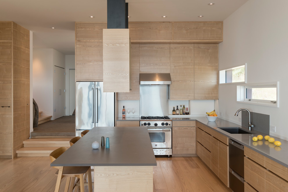 This is an example of a mid-sized contemporary l-shaped open plan kitchen in Seattle with an undermount sink, flat-panel cabinets, light wood cabinets, quartz benchtops, grey splashback, slate splashback, stainless steel appliances, with island, brown floor and medium hardwood floors.