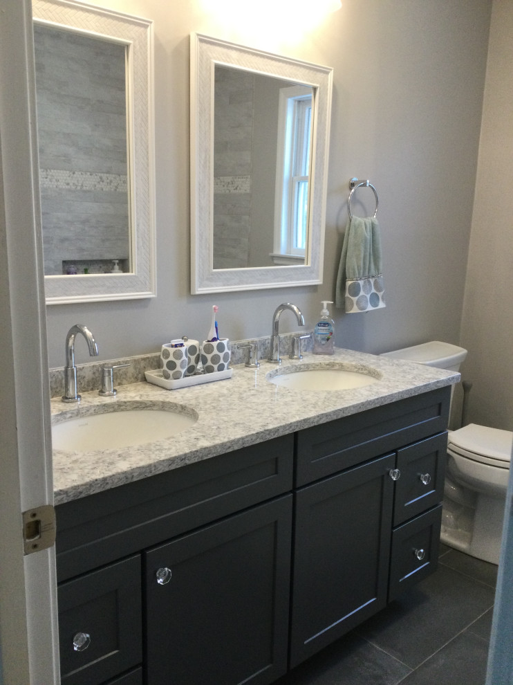 Mid-sized transitional kids bathroom in New York with shaker cabinets, grey cabinets, an alcove tub, a one-piece toilet, gray tile, porcelain tile, grey walls, porcelain floors, an undermount sink, engineered quartz benchtops, grey floor, a shower curtain, grey benchtops, a double vanity and a built-in vanity.