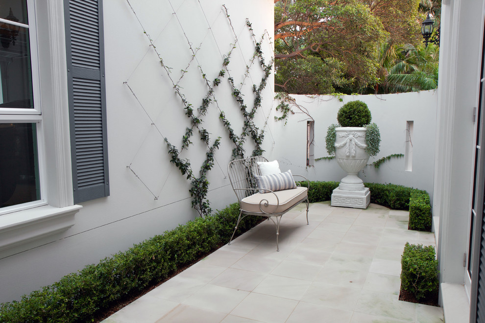 Photo of a small contemporary courtyard shaded outdoor sport court in Sydney with natural stone pavers.