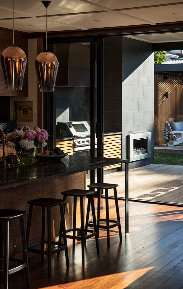 Inspiration for a mid-sized midcentury backyard deck in Auckland with an outdoor kitchen and a roof extension.