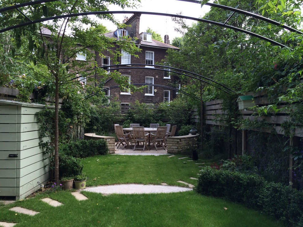 This is an example of a traditional backyard full sun garden in London with a garden path.