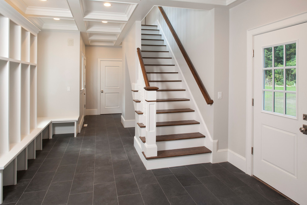 This is an example of a mid-sized mudroom in Boston with beige walls, laminate floors, a single front door, a white front door and black floor.