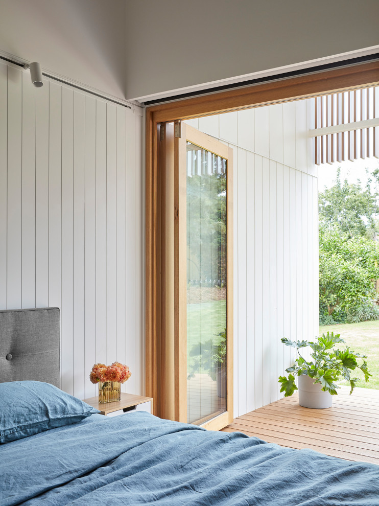 This is an example of a large contemporary master bedroom in Melbourne with white walls, medium hardwood floors, brown floor and planked wall panelling.