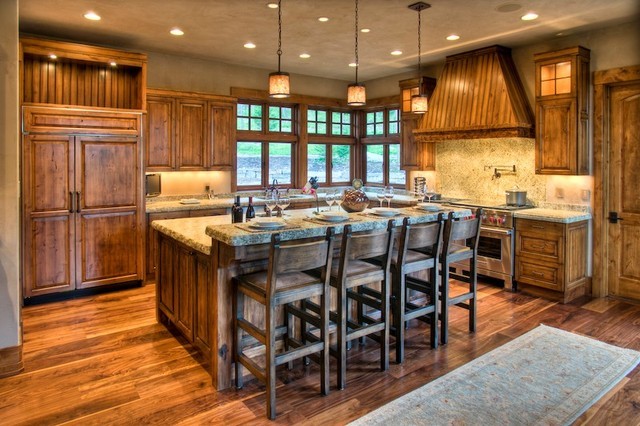Example of a mid-sized mountain style l-shaped medium tone wood floor eat-in kitchen design in Denver with a double-bowl sink, raised-panel cabinets, medium tone wood cabinets, granite countertops, beige backsplash, paneled appliances and an island