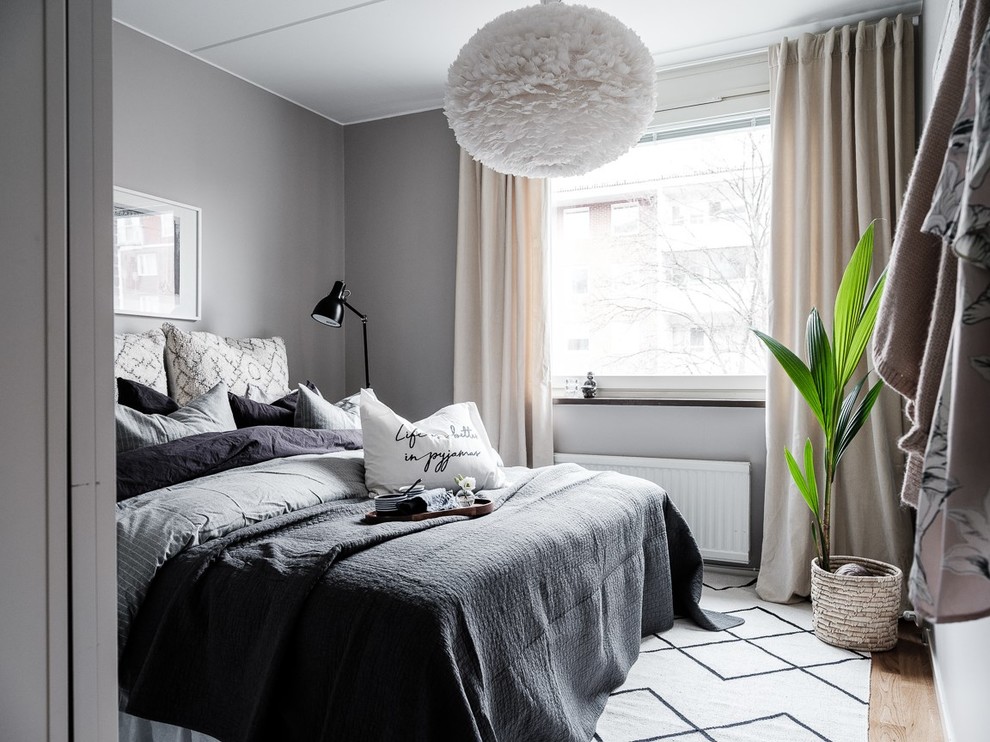Photo of a scandinavian bedroom in Stockholm with grey walls, medium hardwood floors and brown floor.