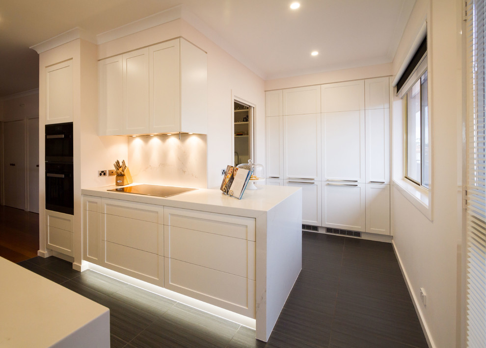 Photo of a large transitional galley eat-in kitchen in Melbourne with a drop-in sink, shaker cabinets, white cabinets, quartz benchtops, stone slab splashback, black appliances and with island.