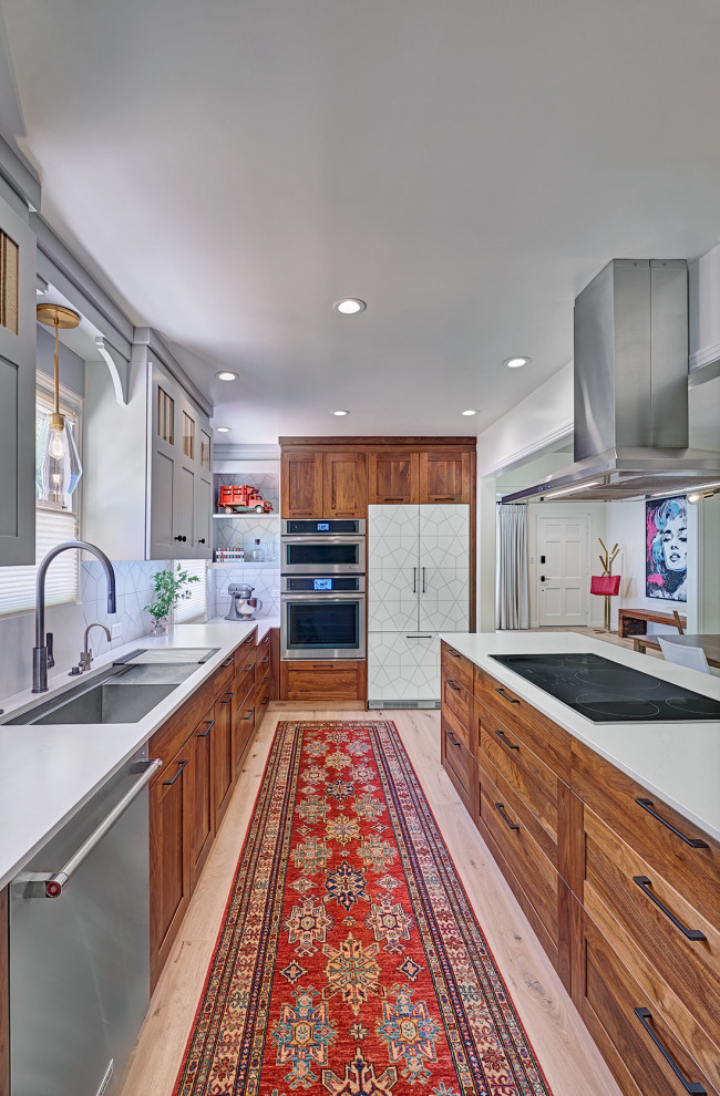 Photo of a mid-sized eclectic u-shaped eat-in kitchen in Sacramento with an undermount sink, shaker cabinets, medium wood cabinets, quartz benchtops, white splashback, porcelain splashback, stainless steel appliances, light hardwood floors, a peninsula, multi-coloured floor and white benchtop.