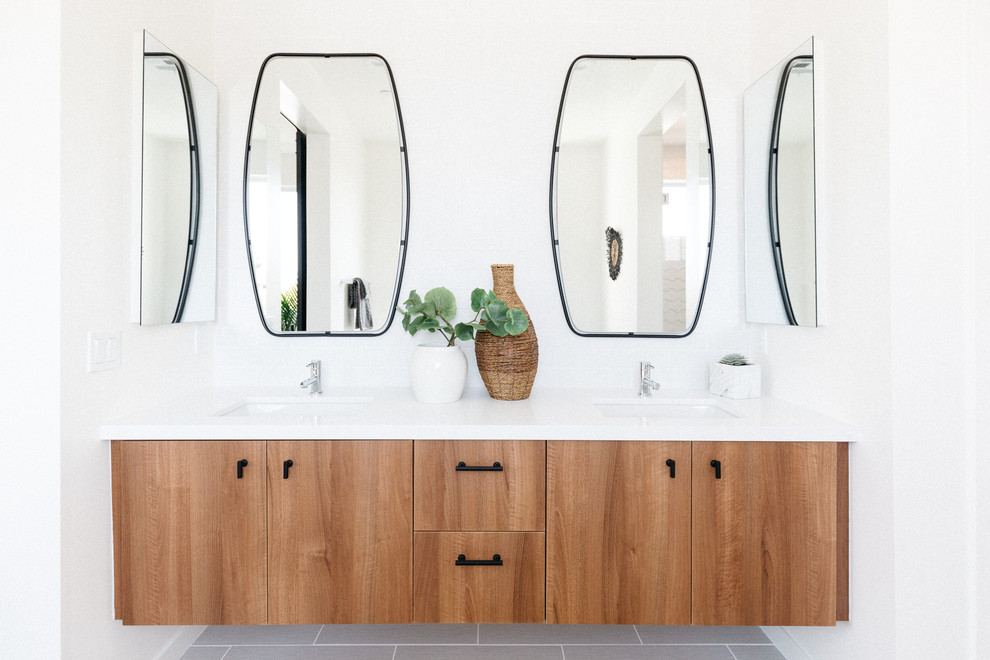 Beach style bathroom in Los Angeles with flat-panel cabinets, white walls, an undermount sink, grey floor and medium wood cabinets.