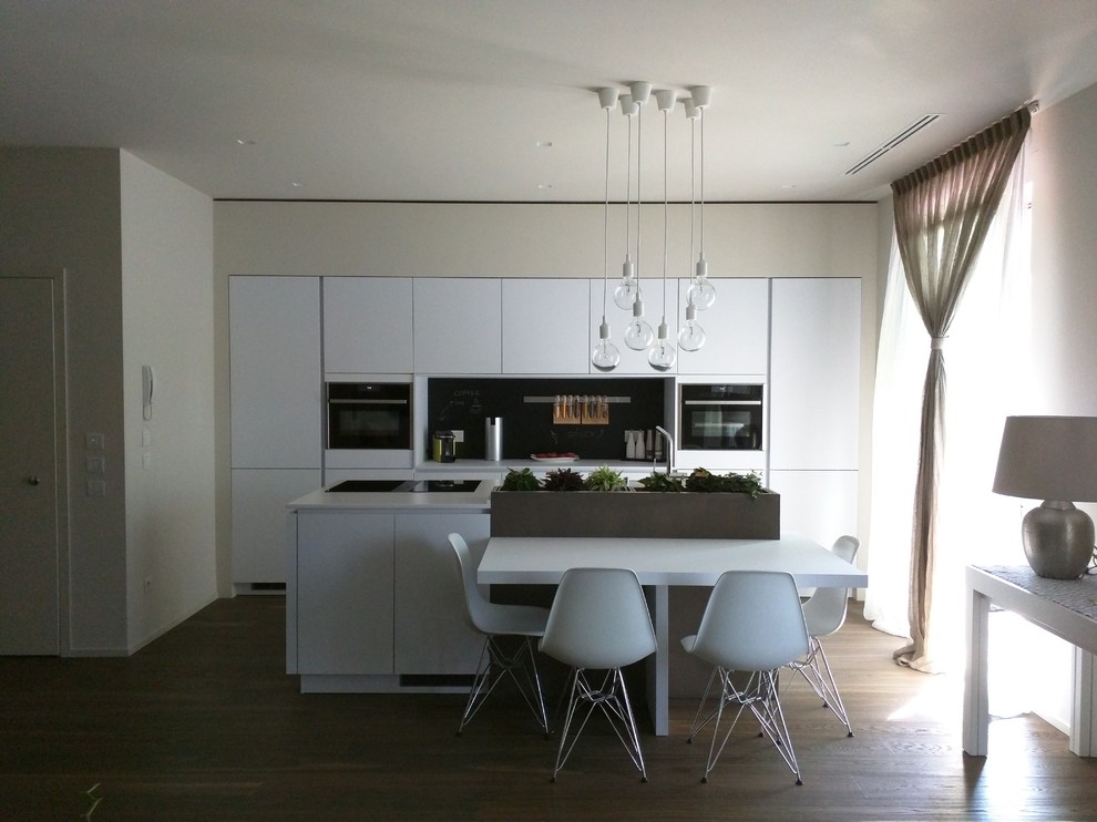 Immagine di una grande sala da pranzo aperta verso la cucina contemporanea con pareti bianche e parquet scuro