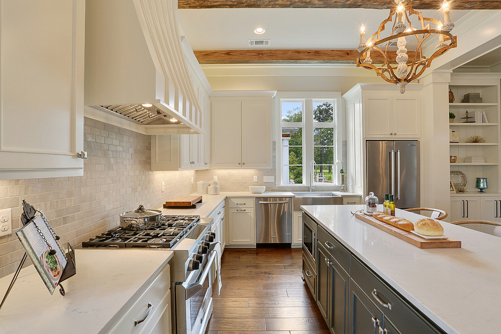 Open concept kitchen - large transitional l-shaped medium tone wood floor open concept kitchen idea in New Orleans with a farmhouse sink, recessed-panel cabinets, white cabinets, white backsplash, subway tile backsplash, stainless steel appliances and an island