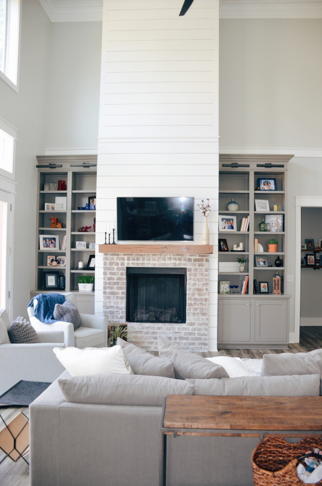 Inspiration for a farmhouse open concept light wood floor and beige floor living room remodel in Other with gray walls, a standard fireplace, a brick fireplace and a wall-mounted tv