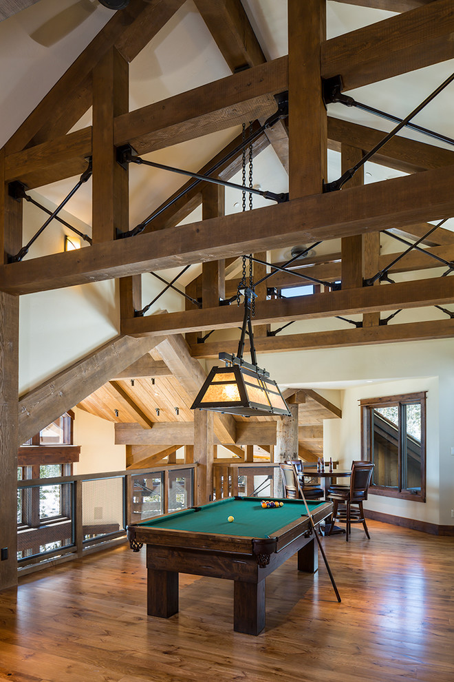Large mountain style loft-style medium tone wood floor and brown floor game room photo with beige walls