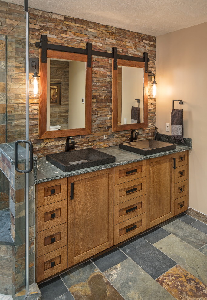 Photo of a country master bathroom in Omaha with shaker cabinets, medium wood cabinets, a freestanding tub, an open shower, brown tile, stone tile and soapstone benchtops.