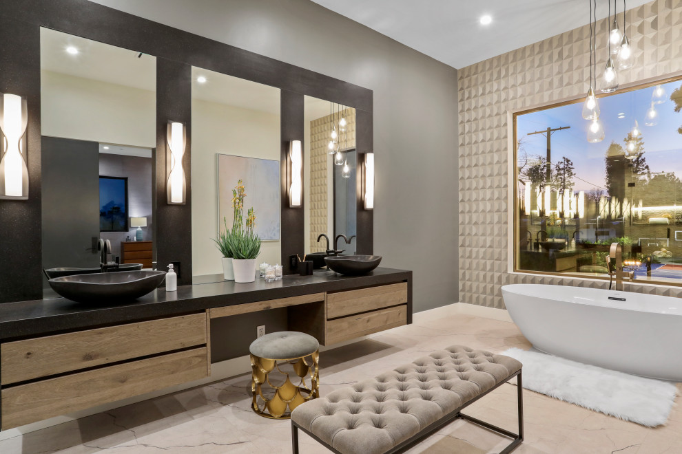 Design ideas for an expansive contemporary master bathroom in Los Angeles with flat-panel cabinets, beige cabinets, a freestanding tub, beige tile, gray tile, porcelain tile, grey walls, a vessel sink, beige floor and black benchtops.