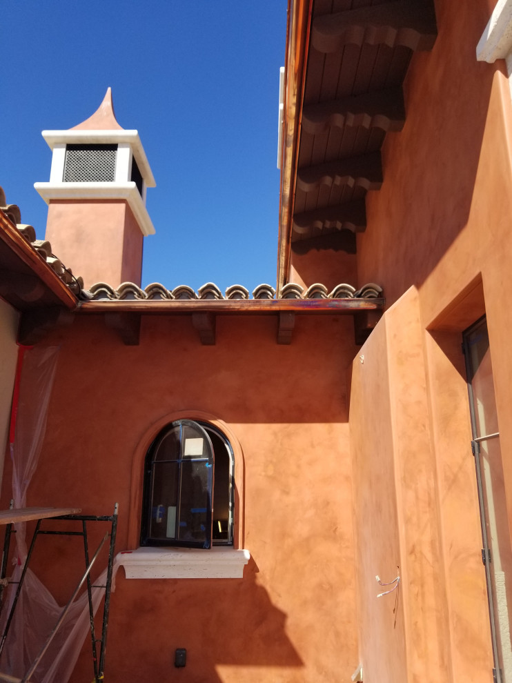 Пример оригинального дизайна: большой, двухэтажный, оранжевый частный загородный дом в средиземноморском стиле с облицовкой из цементной штукатурки, двускатной крышей, черепичной крышей и красной крышей