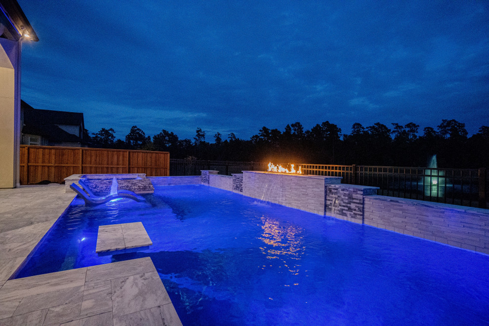 Large modern backyard rectangular pool in Houston with natural stone pavers.