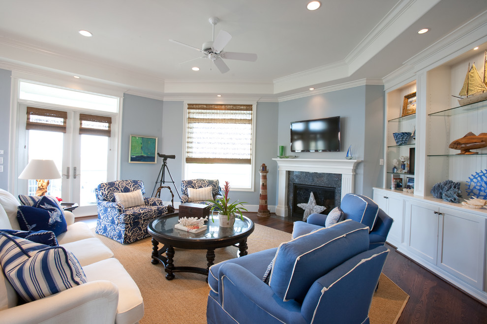 Photo of a large beach style open concept living room in Houston with blue walls, dark hardwood floors, a standard fireplace, a stone fireplace surround and a wall-mounted tv.