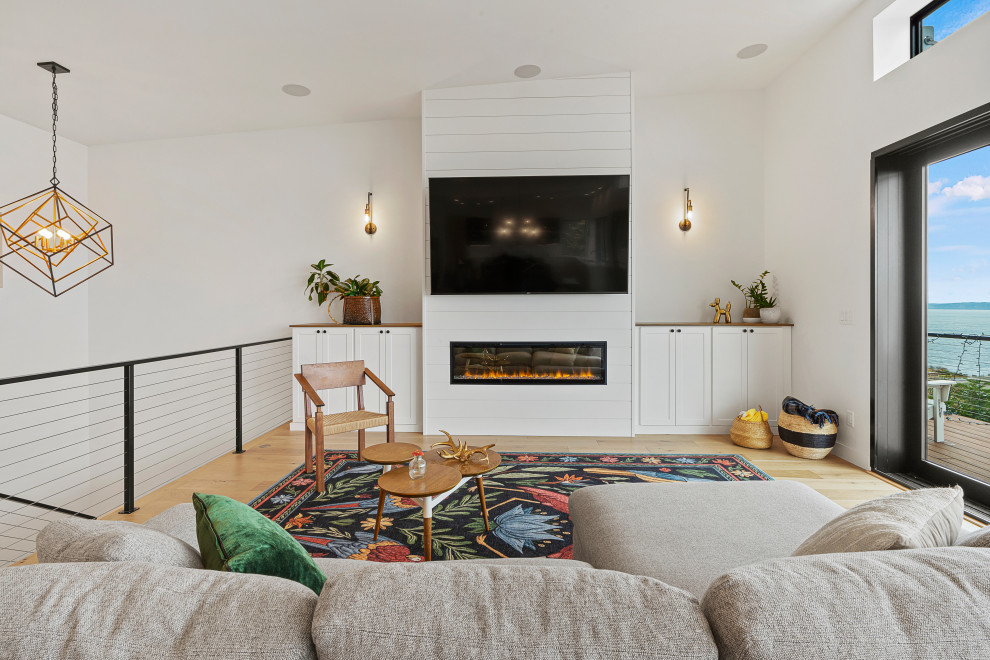 Living room - mid-sized modern open concept medium tone wood floor and vaulted ceiling living room idea in Seattle with white walls, a standard fireplace, a shiplap fireplace and a wall-mounted tv