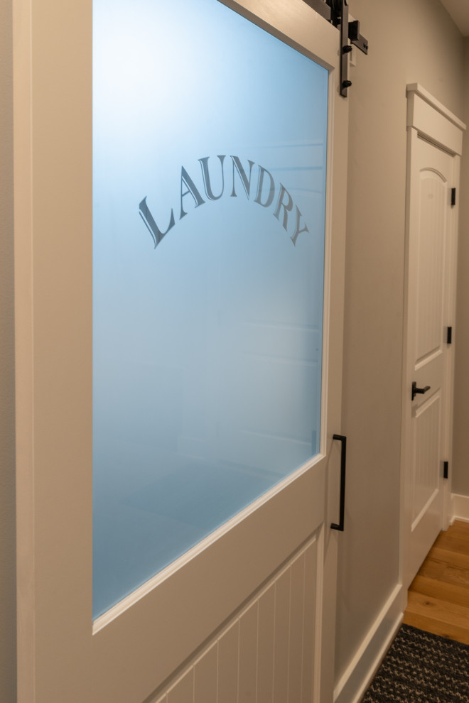 Design ideas for a large modern laundry room in Milwaukee with recessed-panel cabinets, light wood cabinets, white walls, ceramic floors, grey floor and planked wall panelling.