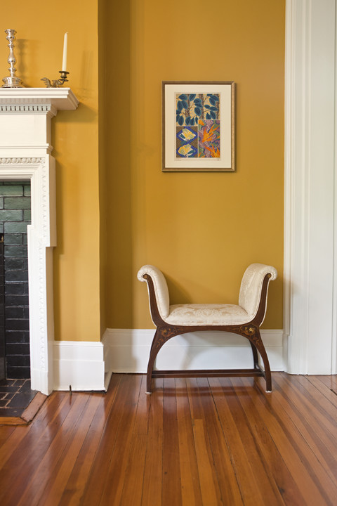 Photo of an eclectic separate dining room in New York with yellow walls and light hardwood floors.