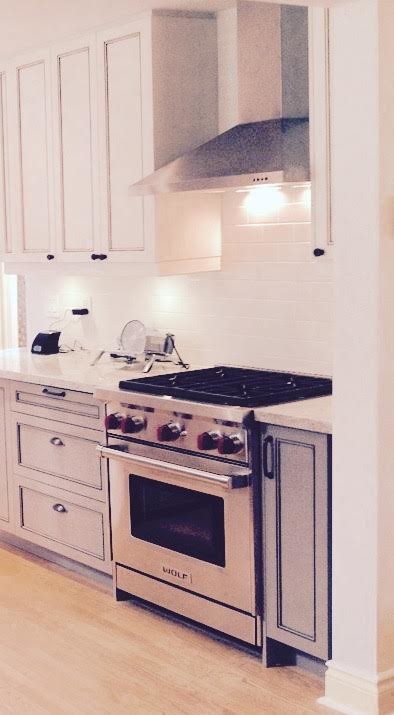 Example of a mid-sized transitional u-shaped light wood floor open concept kitchen design in Toronto with a farmhouse sink, recessed-panel cabinets, distressed cabinets, granite countertops, white backsplash, stainless steel appliances, a peninsula and ceramic backsplash