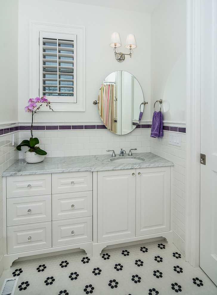 This is an example of a traditional bathroom in Calgary with raised-panel cabinets, white cabinets, marble benchtops, mosaic tile floors, an undermount sink, white tile, subway tile and white walls.