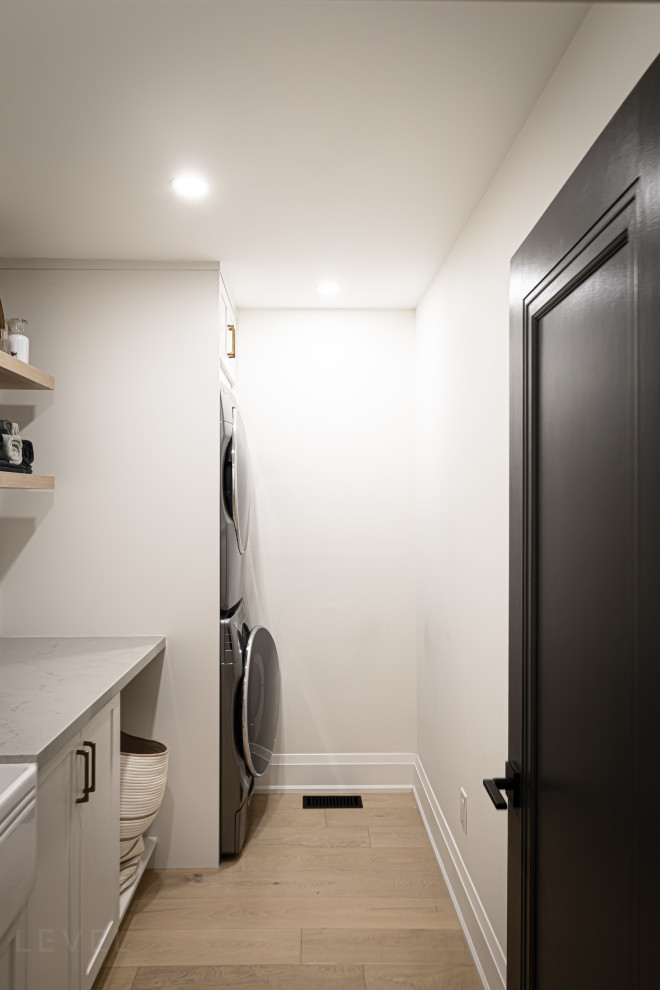 Inspiration för en mellanstor funkis grå linjär grått tvättstuga enbart för tvätt, med en rustik diskho, skåp i shakerstil, vita skåp, laminatbänkskiva, vita väggar, ljust trägolv, en tvättpelare och brunt golv