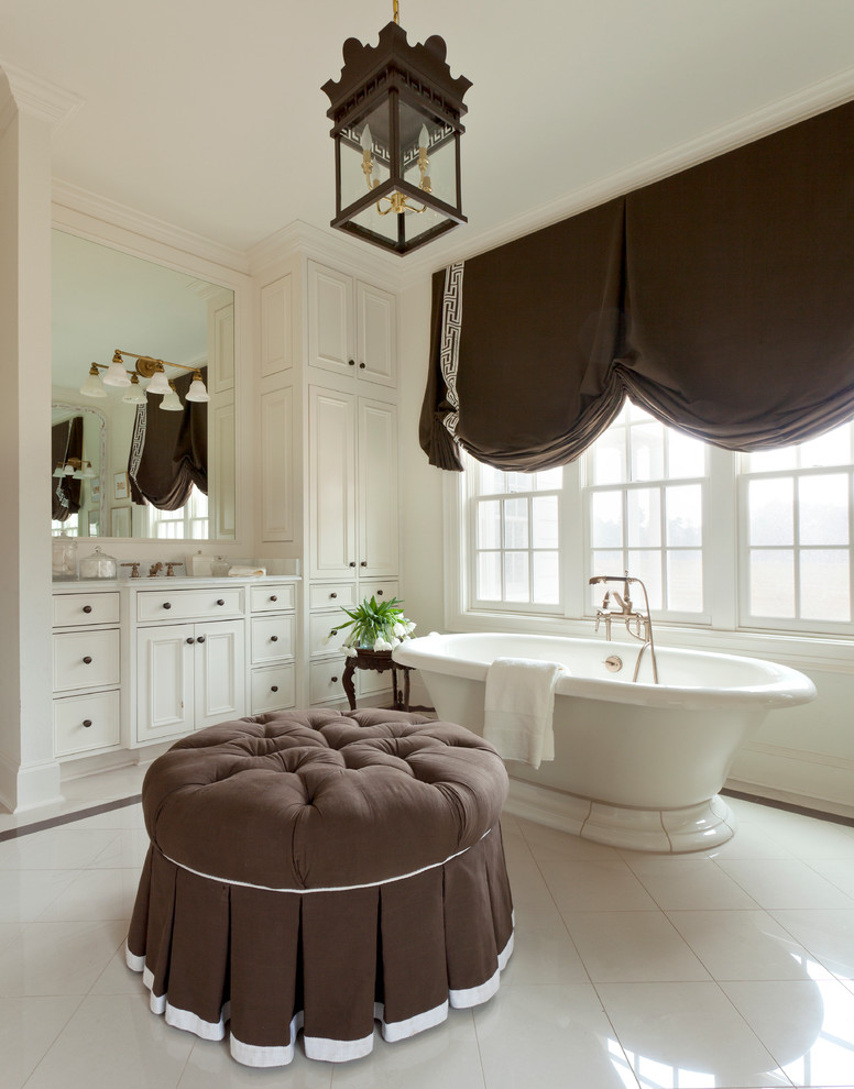 Large transitional master bathroom in Little Rock with beaded inset cabinets, white cabinets, a freestanding tub, a one-piece toilet, white tile, ceramic tile, white walls, ceramic floors, an undermount sink and marble benchtops.