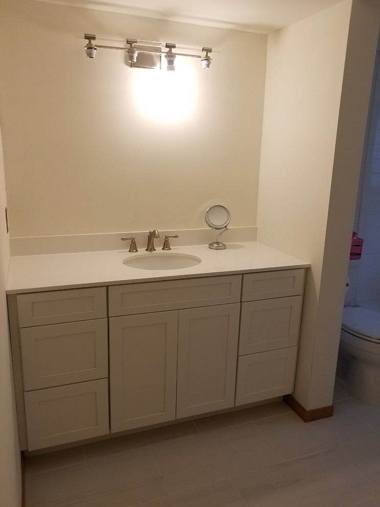 Inspiration for a mid-sized transitional 3/4 white tile and subway tile laminate floor and beige floor alcove bathtub remodel with a two-piece toilet, beige walls, solid surface countertops, white countertops, shaker cabinets, white cabinets and an undermount sink