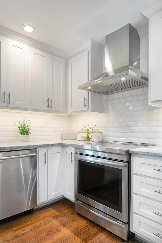 Photo of a small transitional u-shaped eat-in kitchen in Other with an undermount sink, shaker cabinets, white cabinets, granite benchtops, white splashback, subway tile splashback, stainless steel appliances, medium hardwood floors, a peninsula, brown floor and white benchtop.