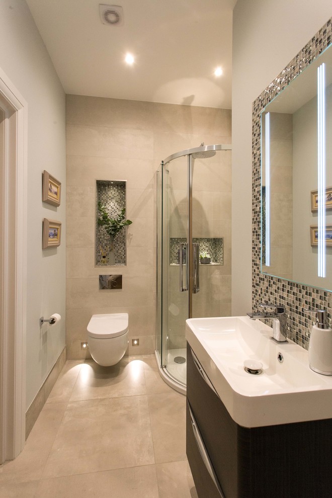 This is an example of a small transitional 3/4 bathroom in Surrey with flat-panel cabinets, dark wood cabinets, a corner shower, a wall-mount toilet, gray tile, ceramic tile, beige walls, ceramic floors, a drop-in sink, beige floor and a sliding shower screen.